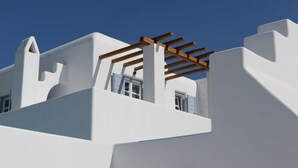 Un edificio blanco con una pérgola de madera y una ventana.
