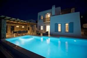 Um edifício moderno com piscina, paredes de pedra e área de estar externa.