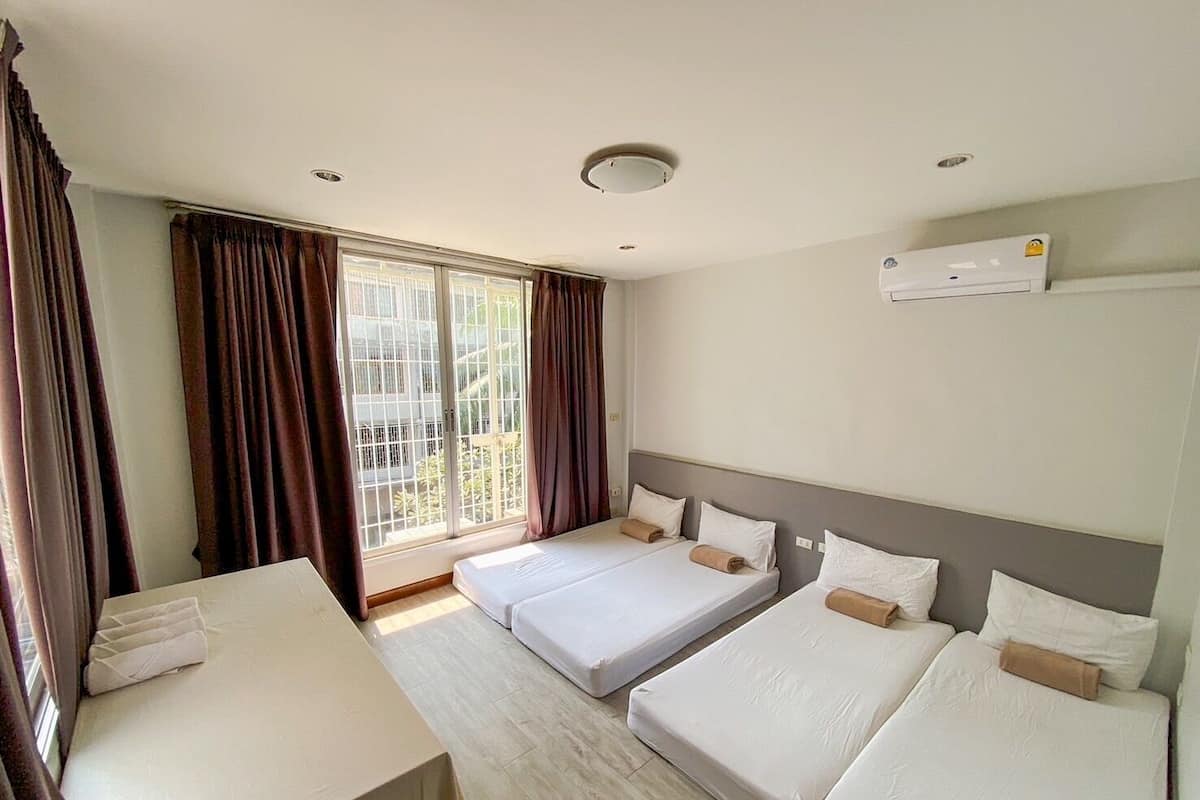 A hotel room with two beds, a desk, and a large window with curtains.