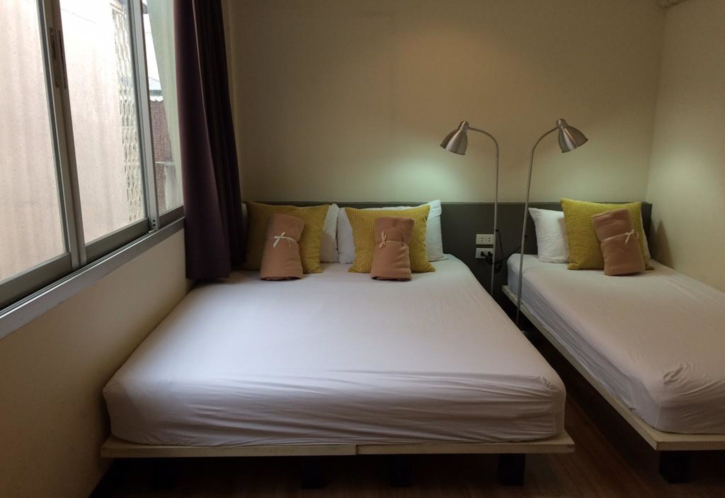 A room with two beds, each with a headboard and bedside lamps.