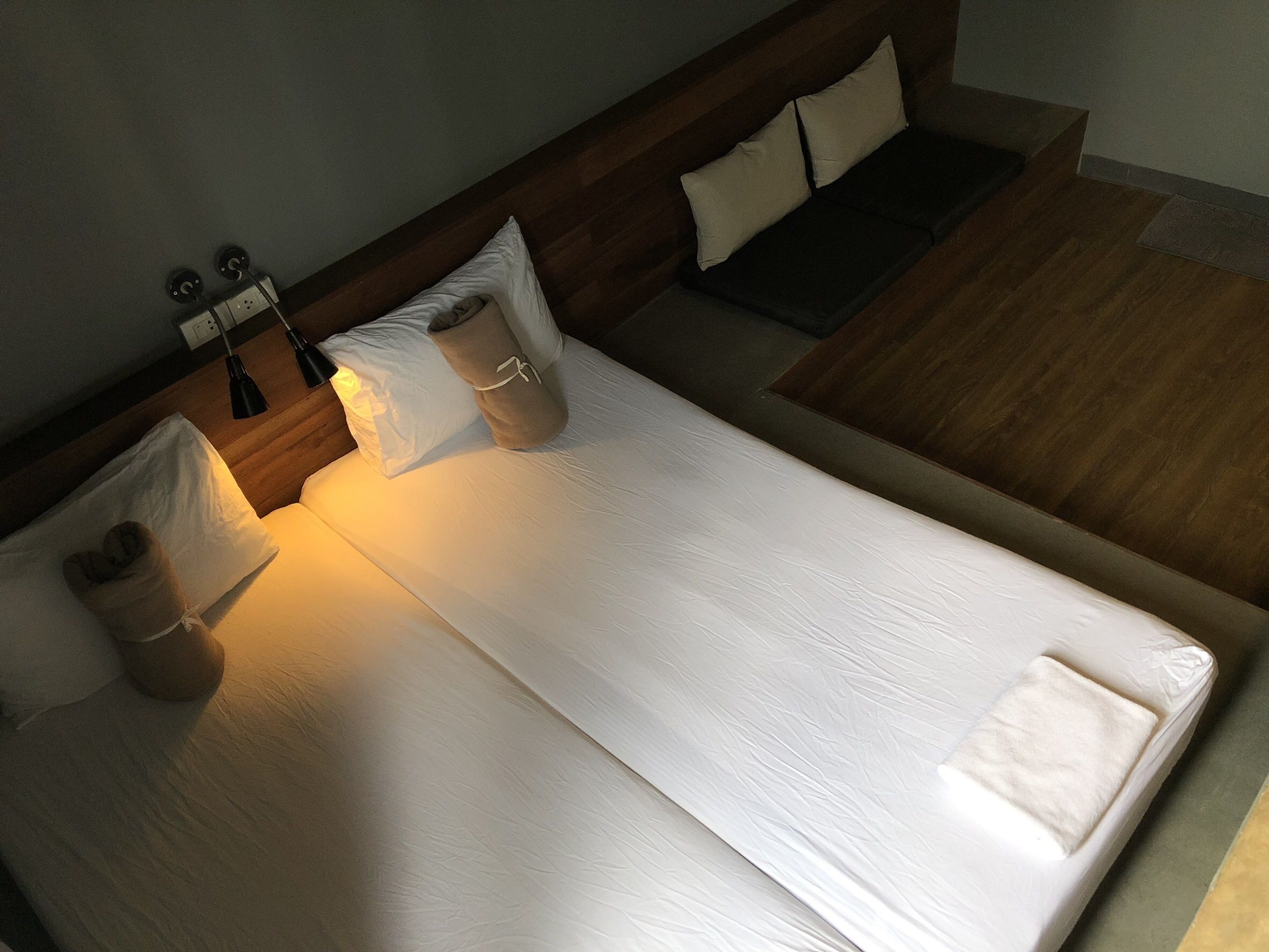 A neatly made bed with white linens, a wooden headboard, and two bedside lamps.
