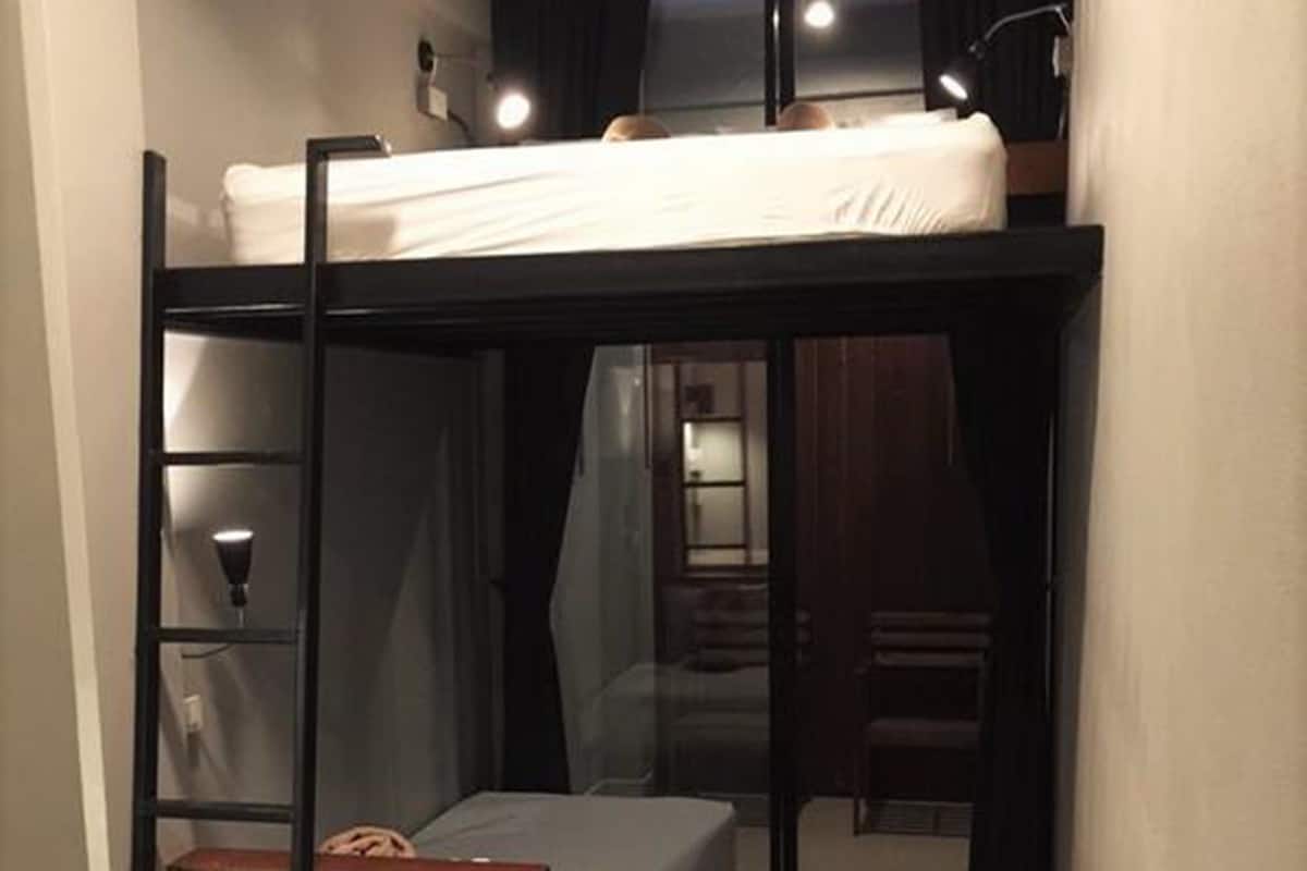 A compact room with a bunk bed, a small desk, and a chair.