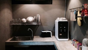 Una cocina pequeña con un lavamanos, un tostador y un microondas.