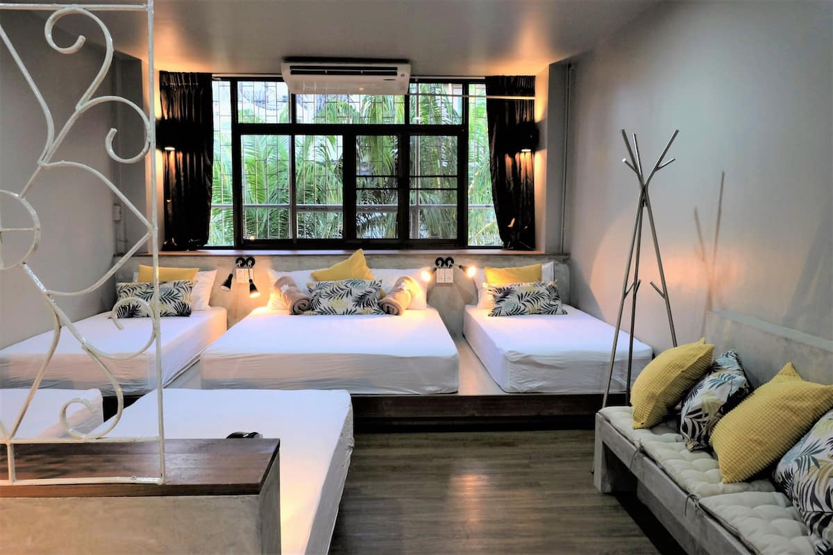 A hotel room with two beds, a sofa, a decorative metal piece, and a window with curtains.