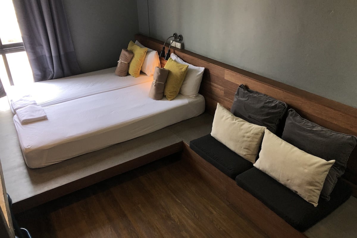 A compact room with a bed, a sofa, and a bedside table.