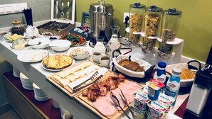 Een ontbijtbuffet met diverse soorten eten, zoals eieren, spek, gebak en ontbijtgranen.