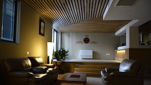 Een moderne woonkamer met leren banken, een houten salontafel en een aan de muur bevestigde televisie.