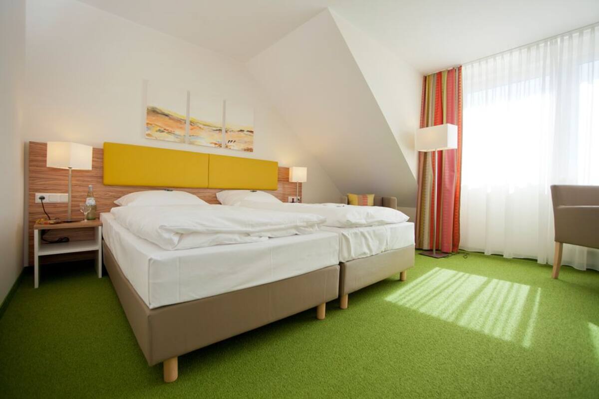 A hotel room with a bed, two bedside tables, a lamp, a desk, and a chair.
