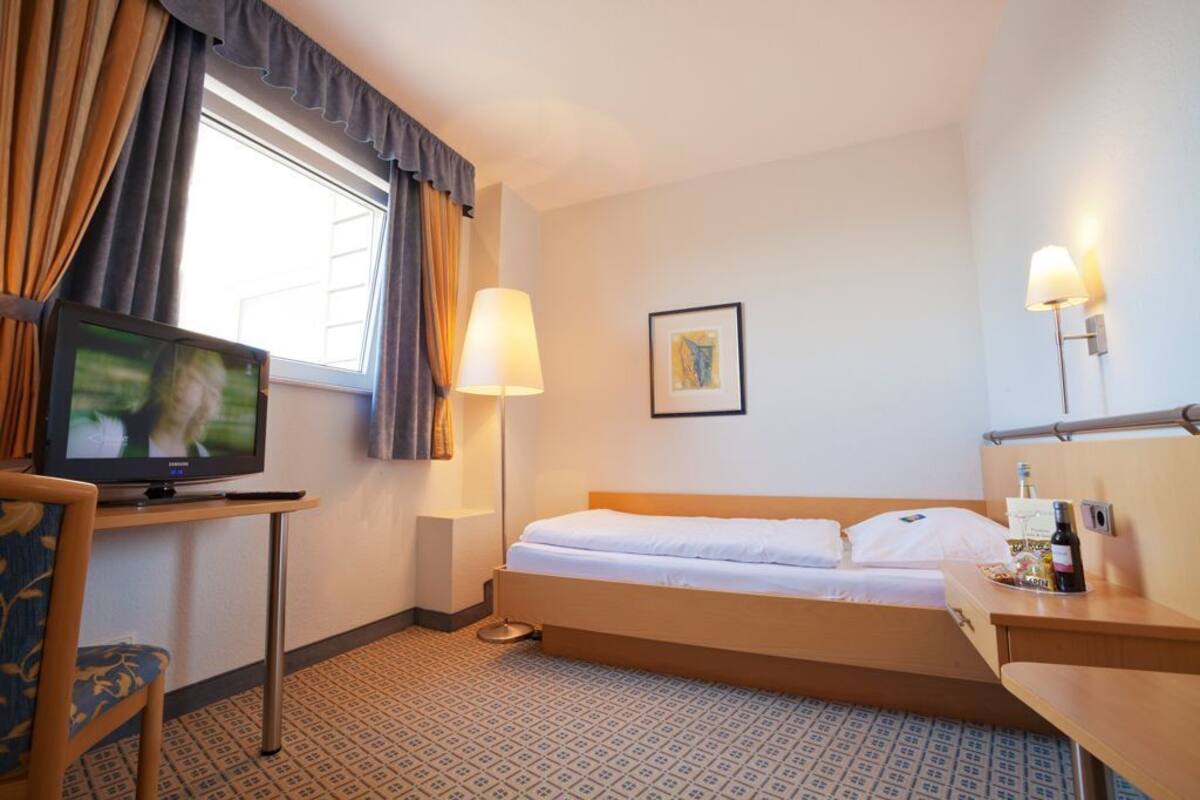 A hotel room with a bed, a television, a desk, and a chair.