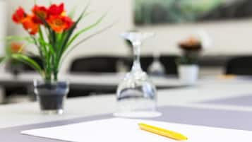 A table with a yellow pen, a glass vase with flowers, and a potted plant.