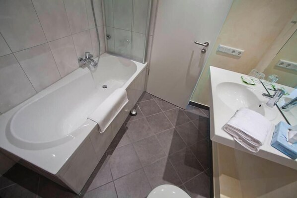 Un baño con bañera, inodoro y lavamanos.