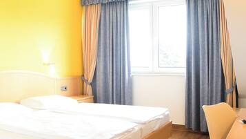 Una habitación de hotel con una cama de madera, un escritorio y una ventana con cortinas.