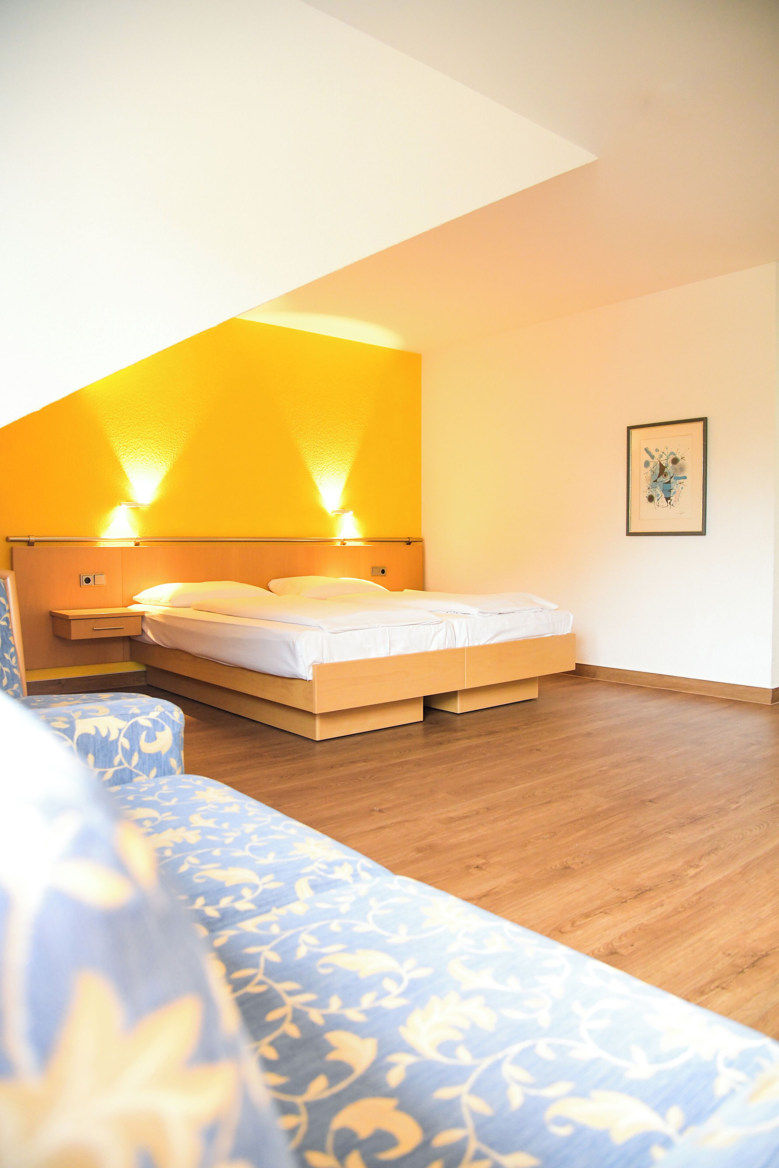 A bedroom with a bed, a bedside table, and a chair.