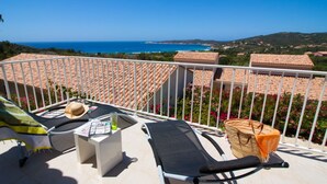 A balcony with a view of the sea, a chair, a table with a hat, and a basket. - Résidence Castugna (Cargese)