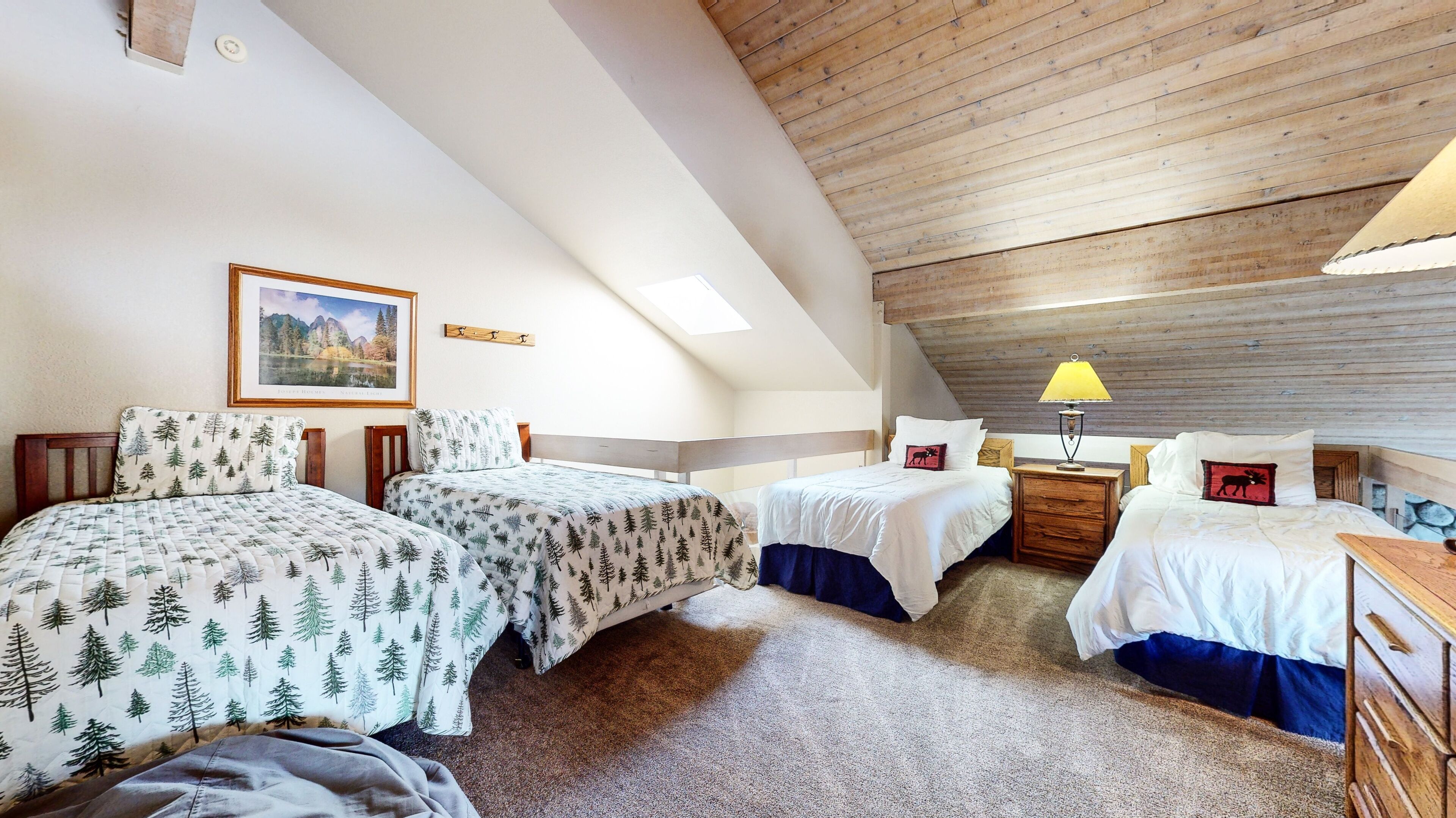 Un dormitorio acogedor con dos camas, techo de madera, tragaluz e imagen de un paisaje enmarco.