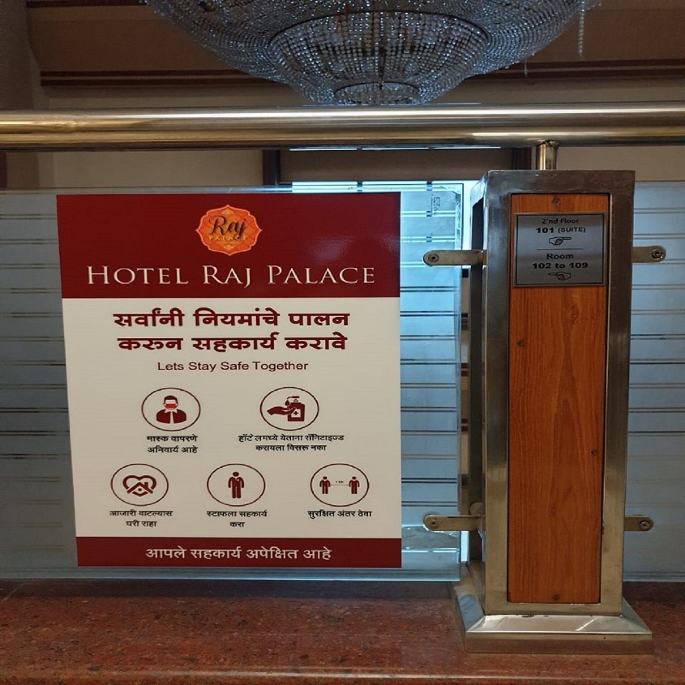 Een bord voor Hotel Raj Palace met veiligheidsrichtlijnen in verschillende talen.