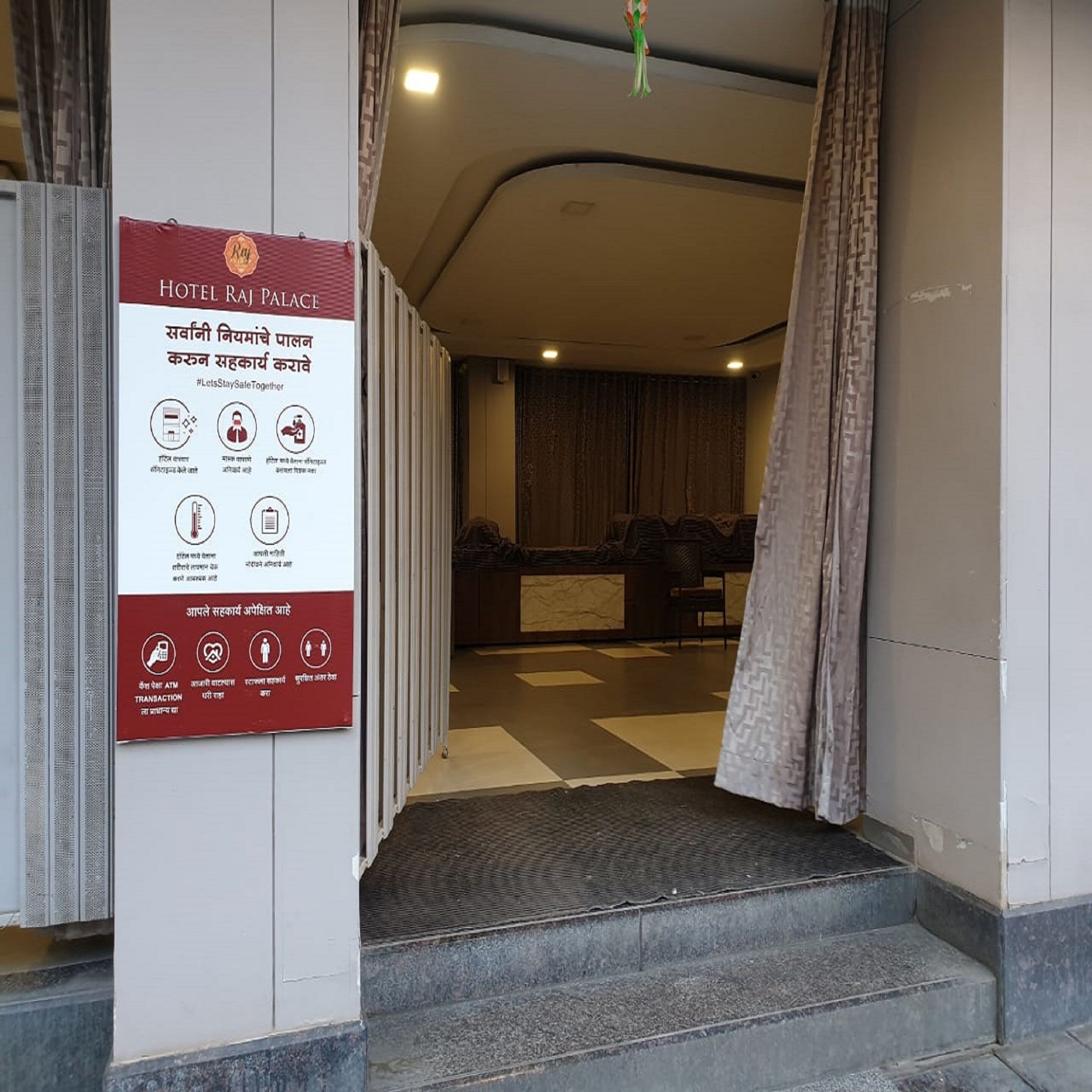 En hotelindgang med et skilt, der viser sikkerhedsforskrifter og faciliteter.