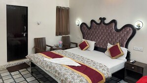 Una habitación de hotel con cama, mesita de noche y aire acondicionado en la pared.