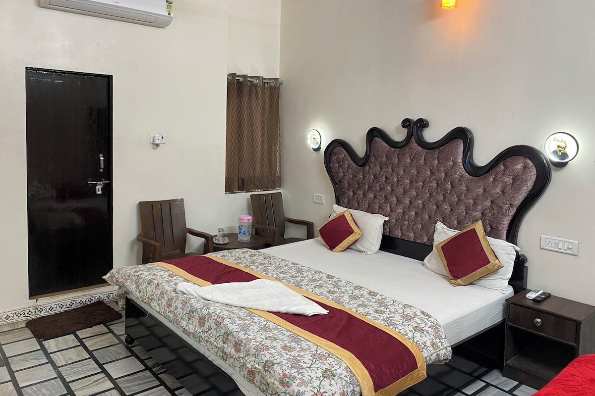 Una habitación de hotel con cama, mesita de noche y aire acondicionado en la pared.