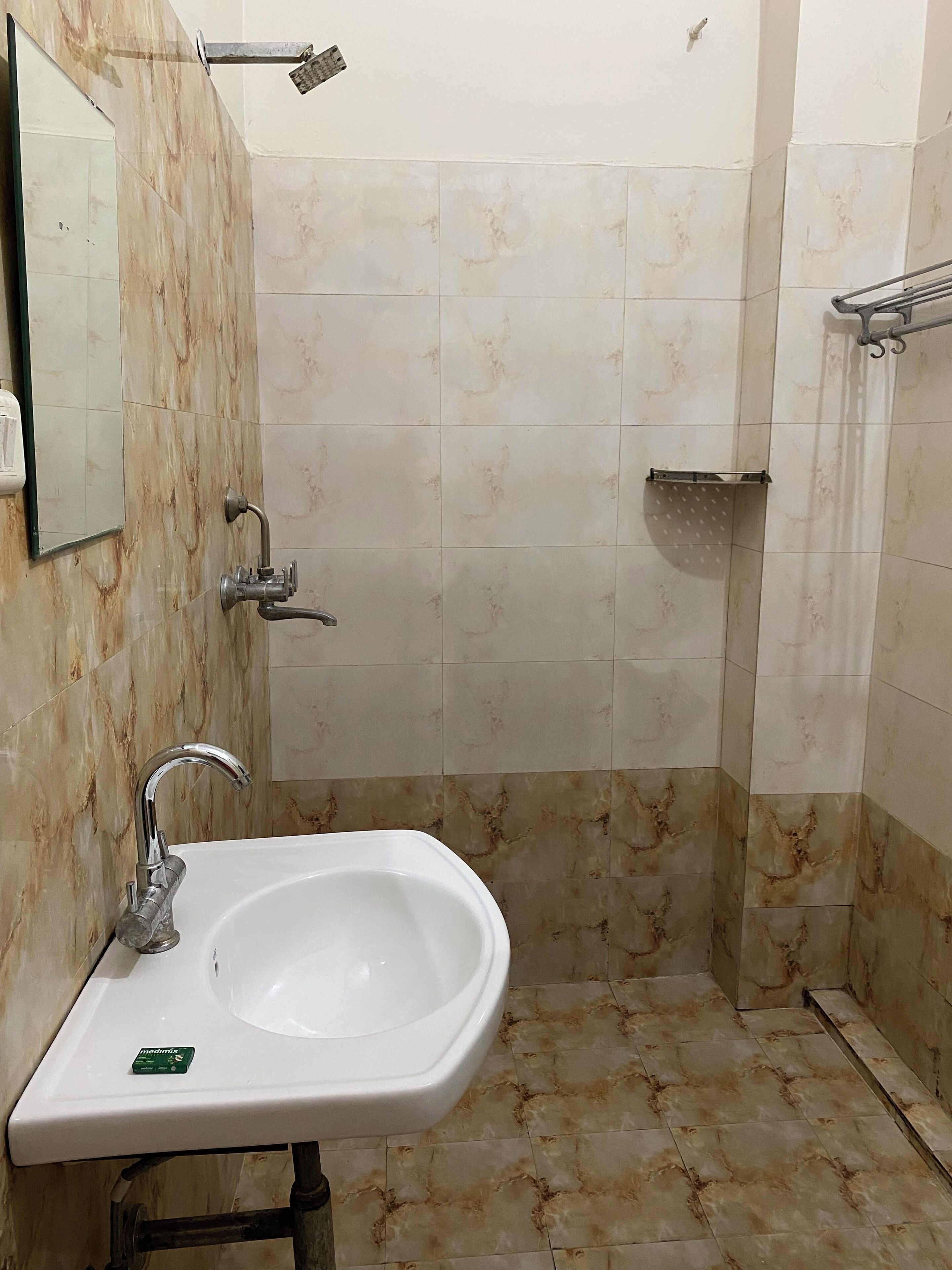 A bathroom with a sink, mirror, shower, and tiled walls.