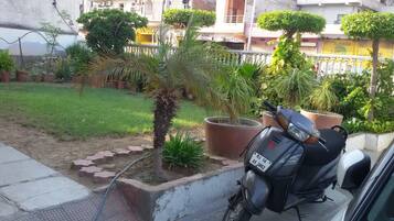 A garden area with potted plants, a parked motorcycle, and a building in the background.