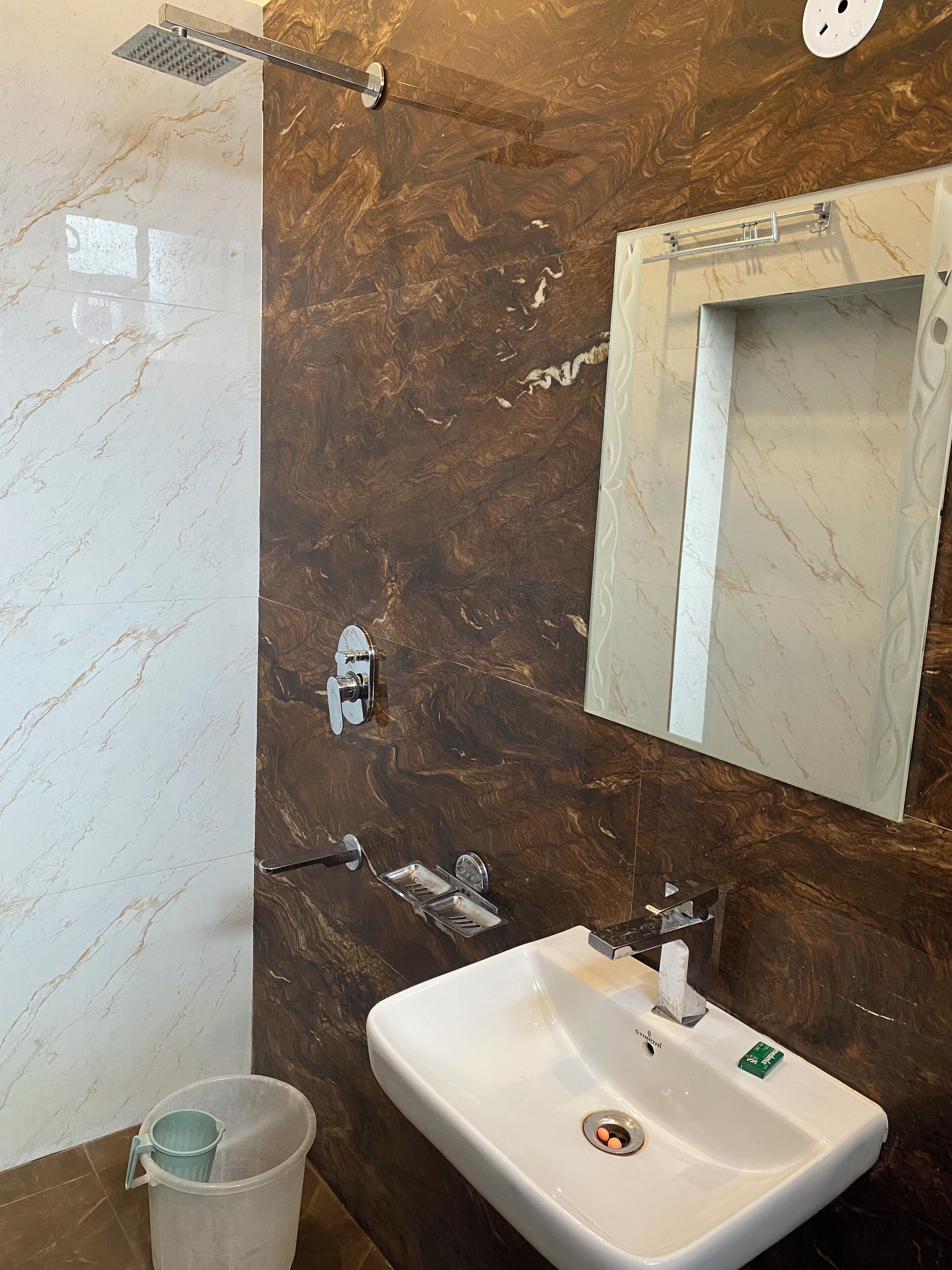 Ein Badezimmer mit einem weißen Waschbecken, einem Spiegel und einer Dusche mit Regendusche.