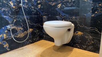 Un baño con inodoro, ducha y pared de mármol.