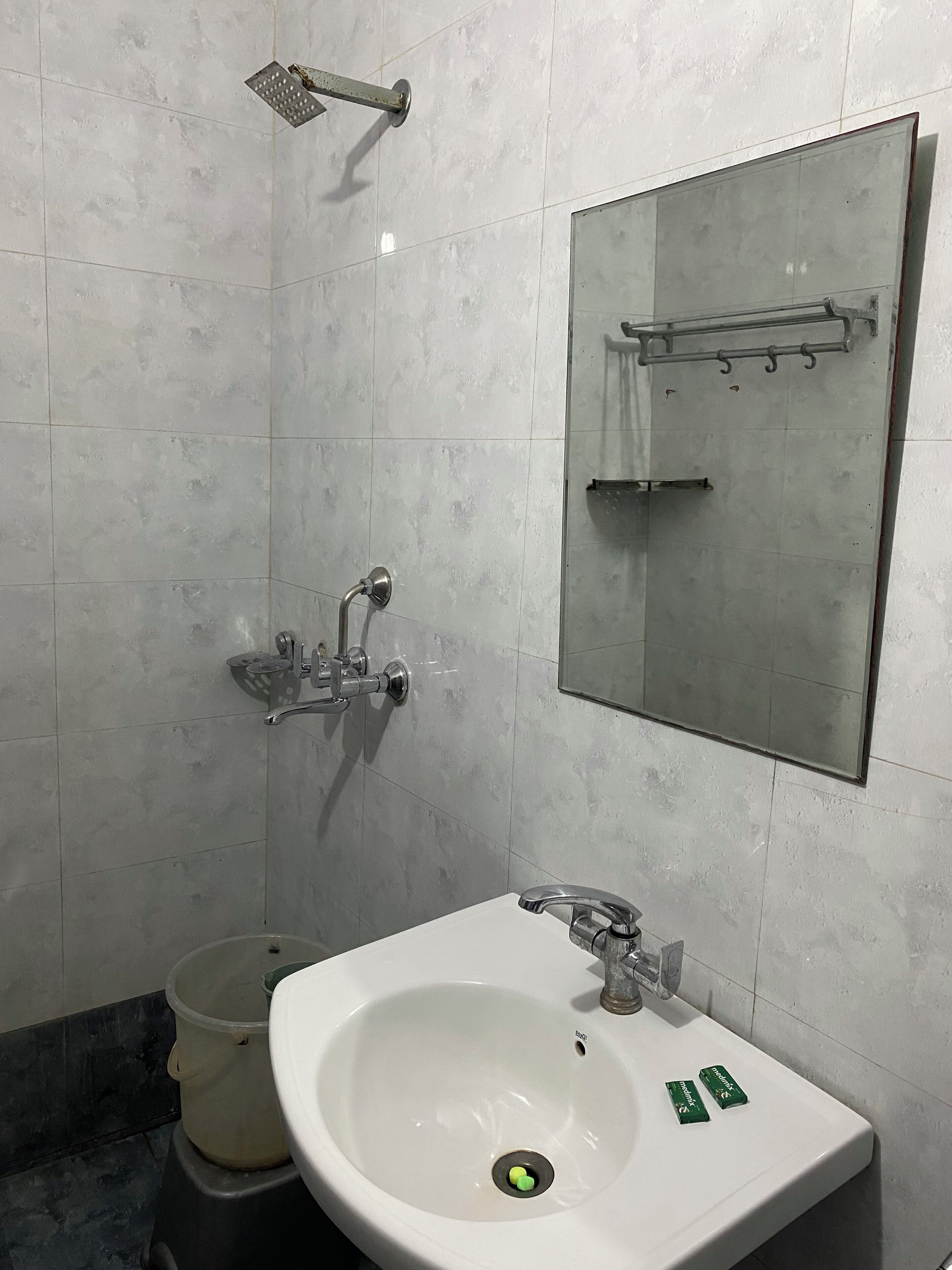 Un baño con lavamanos blanco, ducha y espejo.