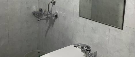 Un baño con lavamanos blanco, ducha y espejo.
