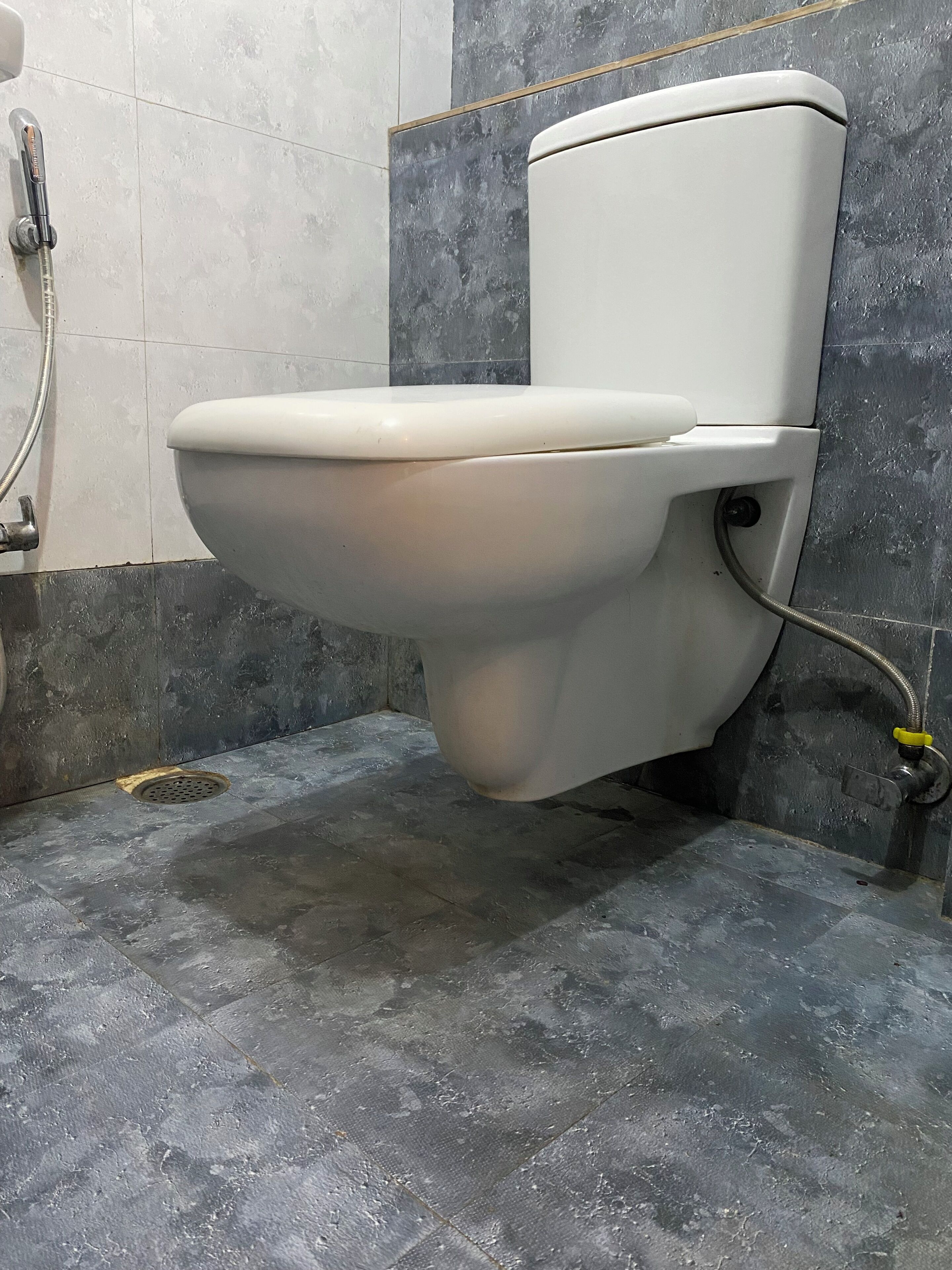Des toilettes dans une salle de bain équipée d’une douche et d’un drain.