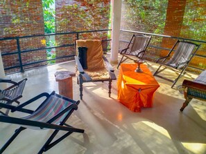 Een balkon met uitzicht op een bakstenen muur en groen, voorzien van stoelen en een tafel.