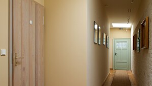 A hallway with wooden doors, framed pictures on the walls, and a light green door at the end. - Alte Remise (Dresden)