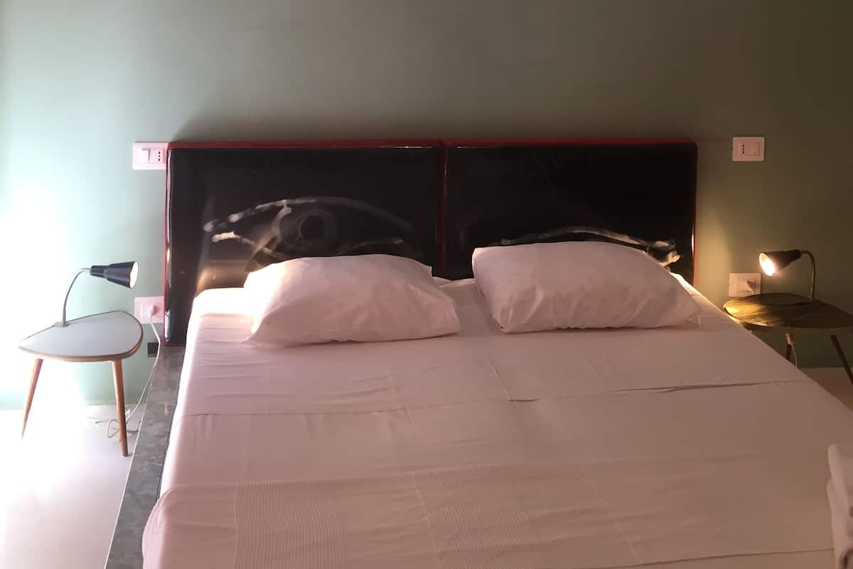 A neatly made bed with white linens in a room with green walls.