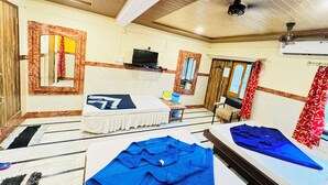 A room with two beds, a television, and a window with curtains. - Shri Ganesh Hotel (Abu Road)