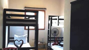 A room with two bunk beds, a desk, a chair, and a wardrobe.