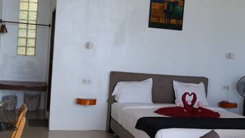 Una habitación de hotel con una cama, una silla de madera, una mesa y un cuadro en la pared.