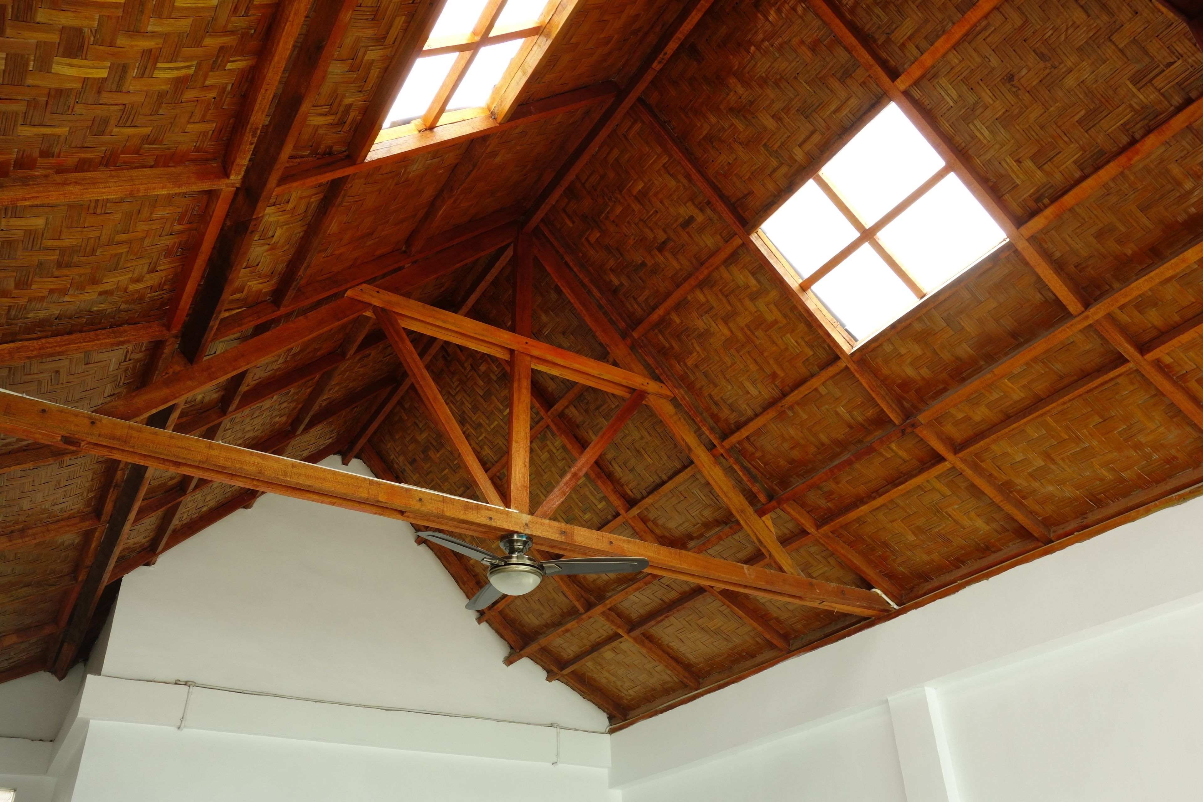 A high ceiling with wooden beams and a fan.