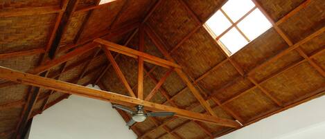 A high ceiling with wooden beams and a fan.