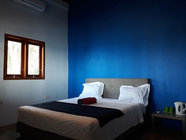 Un dormitorio con cama, mesita de noche y ventana.