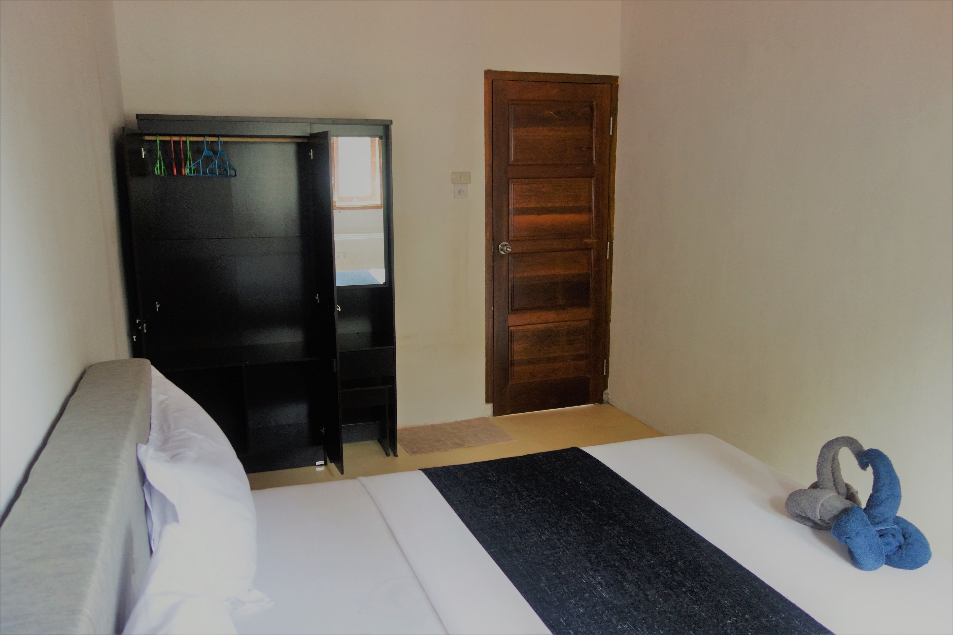 A bedroom with a bed, a wardrobe, and a door.
