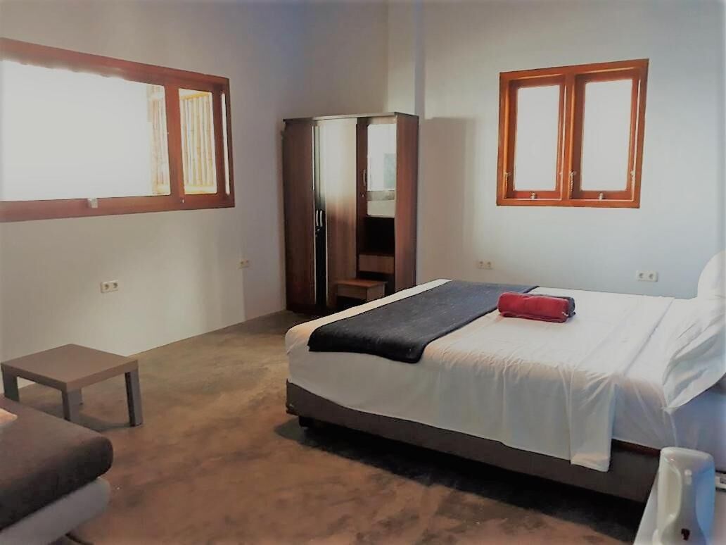 Un dormitorio con cama, mesita de noche, armario y ventana.