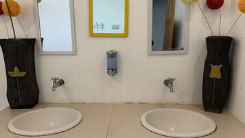 Un baño con dos lavamanos, espejos y jarrones decorativos con pompones.