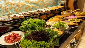 Un bufé con diversos platos, entre ellos ensaladas, verduras y otros alimentos.