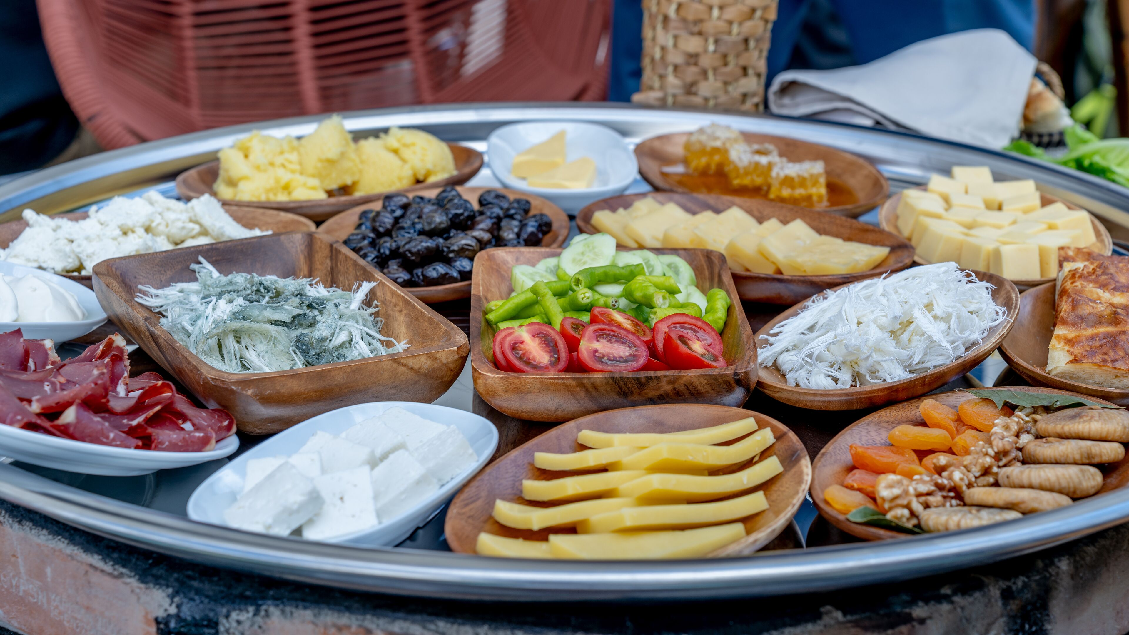 A variety of cheeses, fruits, and vegetables arranged on a tray.