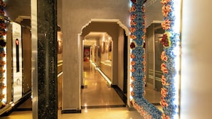 Un pasillo de hotel con columnas de mármol, una larga galería y adornos florales.