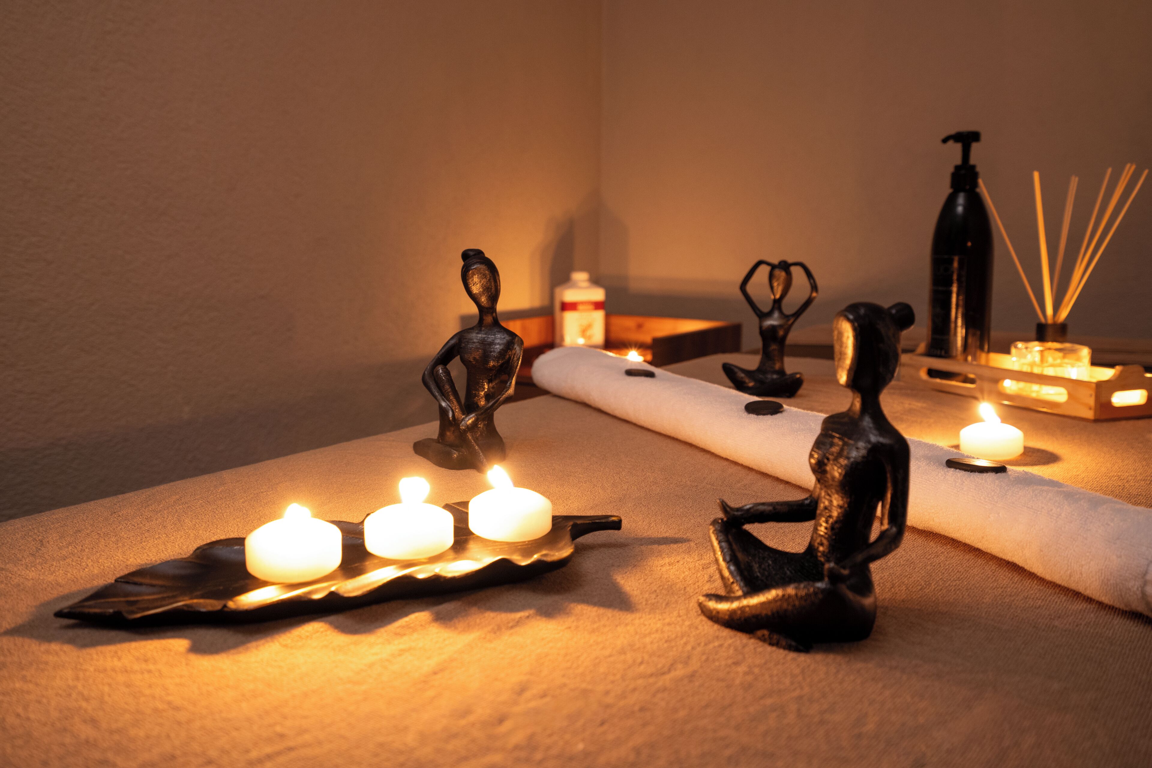A room with a small table holding candles, a bottle of hand sanitizer, and a diffuser.