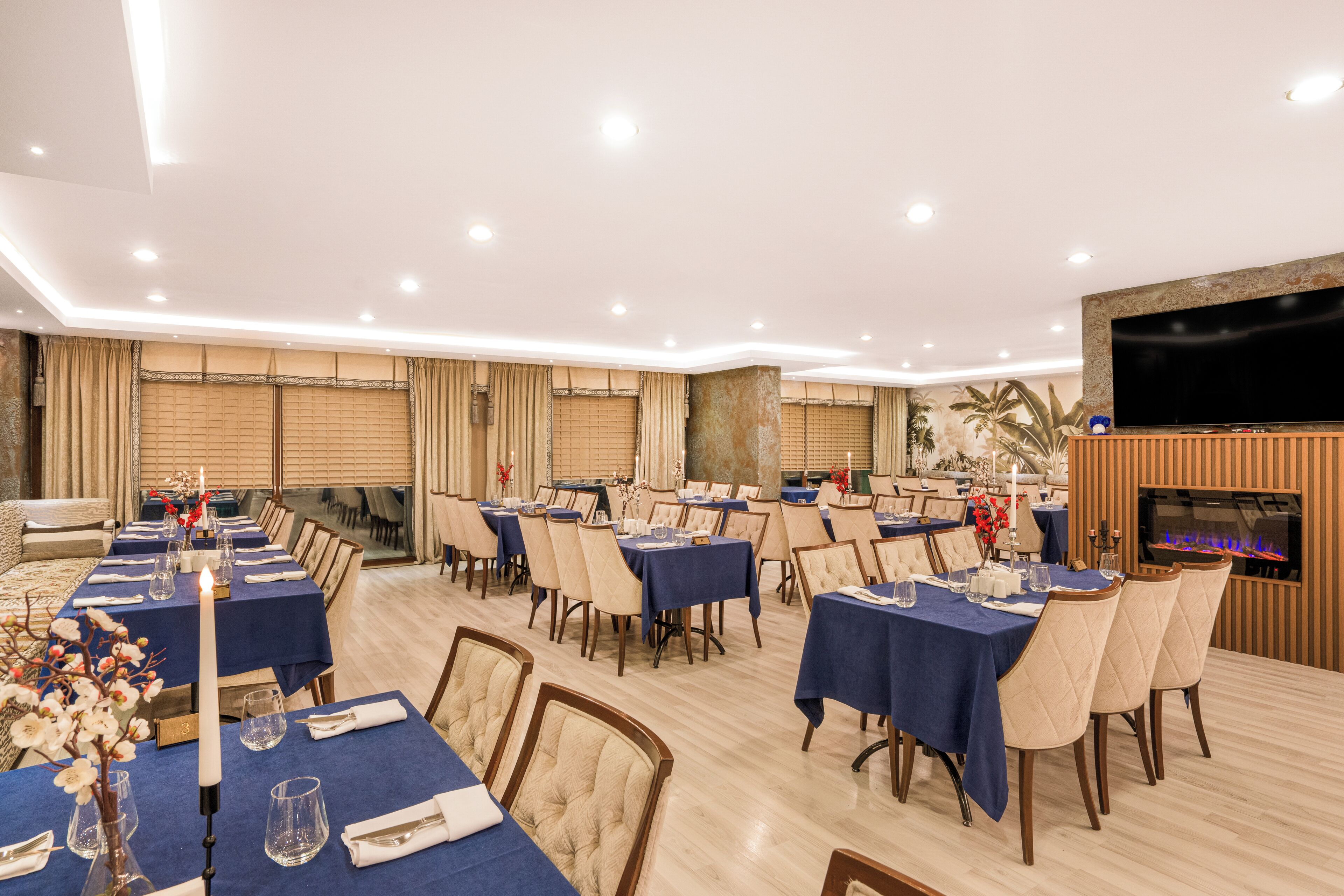 Un coin repas avec des tables dressées pour le repas, un téléviseur fixé au mur et une cheminée.
