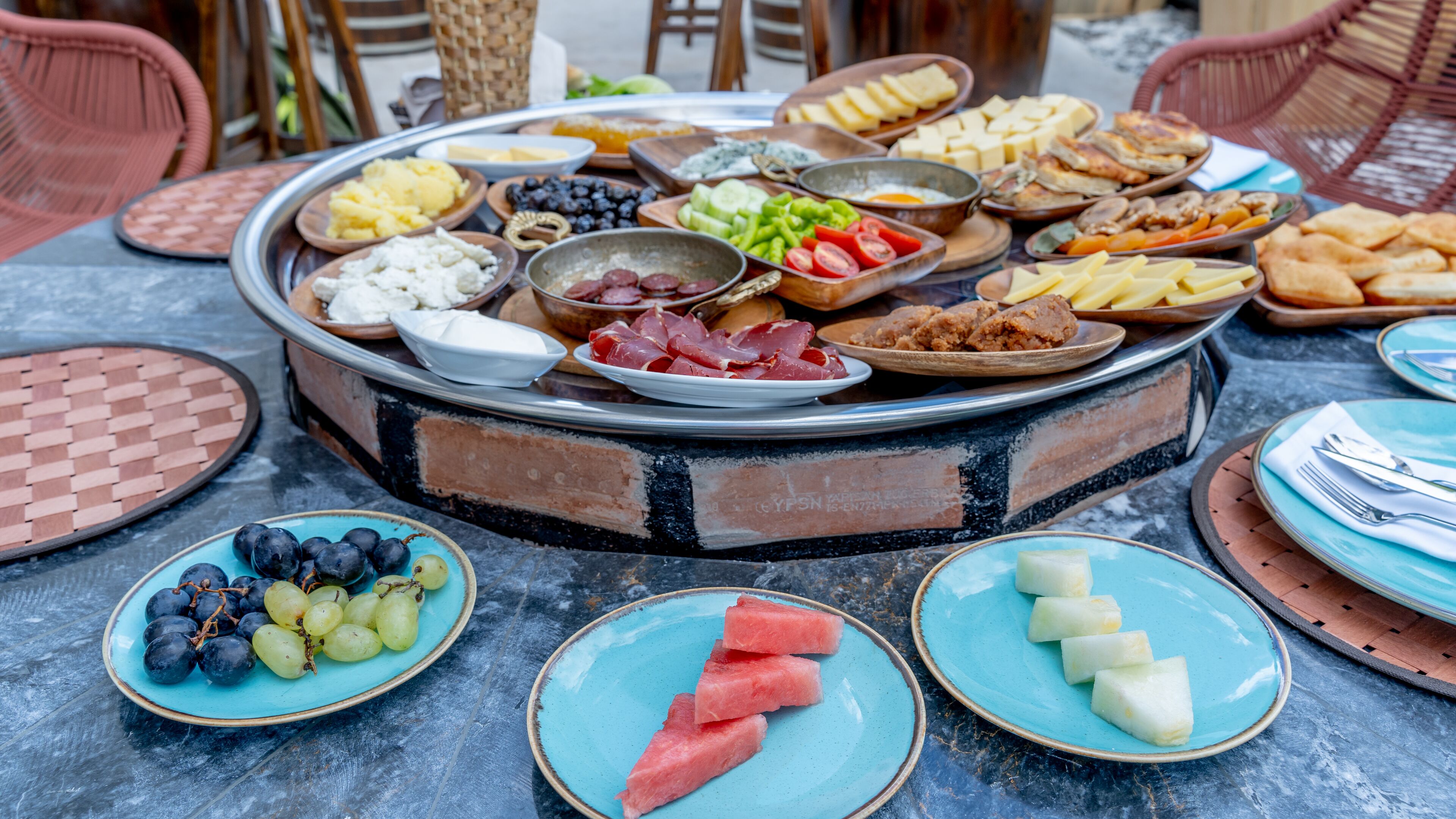 A round table with various food items and plates.