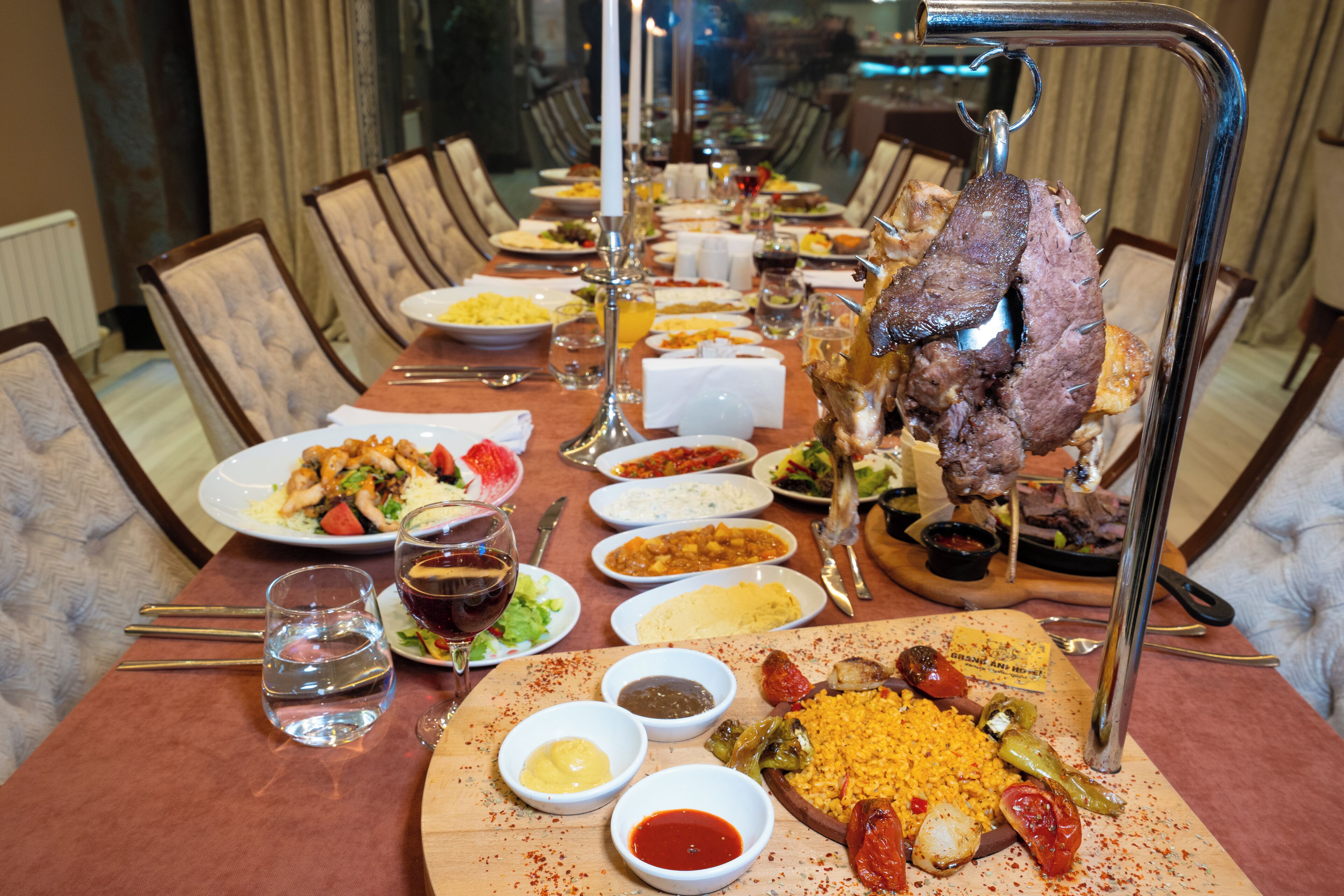 A dining table set with various dishes, including a roasted meat centerpiece, multiple plates of food, and several small bowls of sauces.