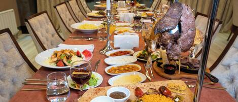 A dining table set with various dishes, including a roasted meat centerpiece, multiple plates of food, and several small bowls of sauces.
